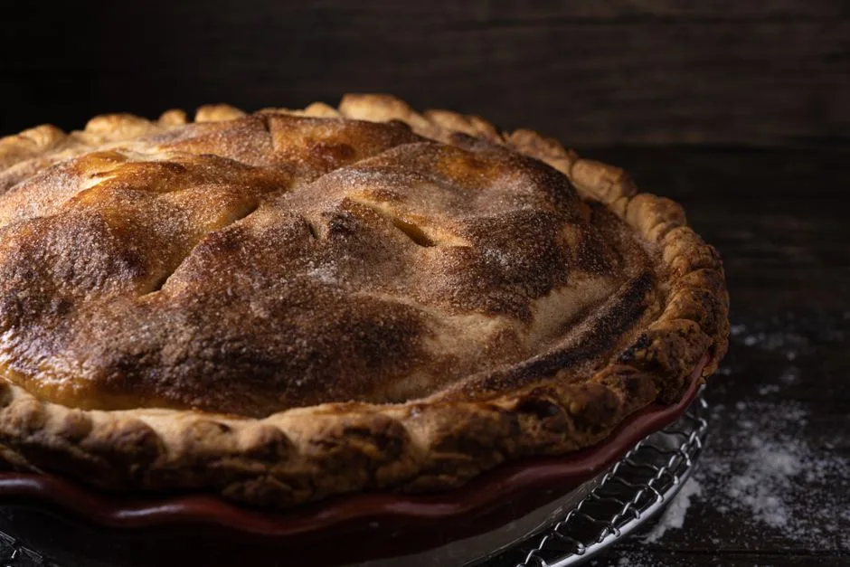 A delicious homemade apple pie with golden crust on a wire rack evokes a rustic, cozy vibe.