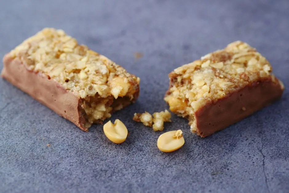 Close-up of a broken chocolate and nut energy bar on a gray surface.