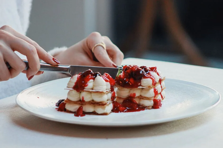Close-up of a delicious mille feuille with berries being sliced, creating a tempting dessert scene.