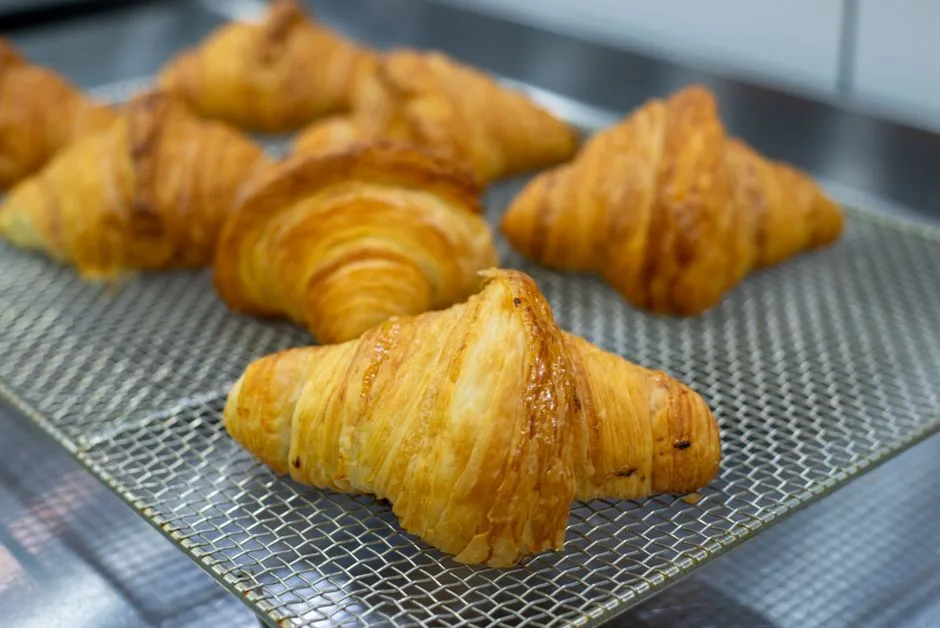 Delicious golden croissants on a cooling rack, showcasing perfect layers and flakiness.