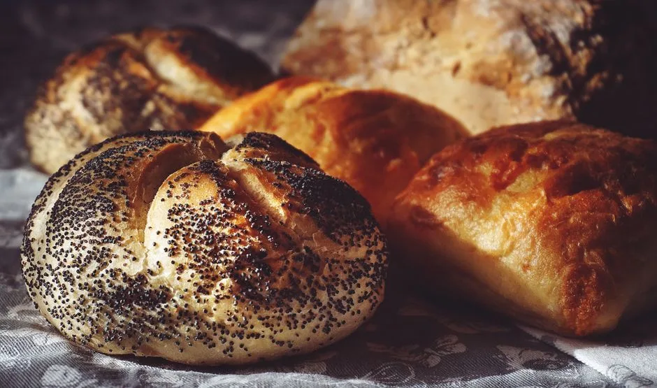 Captivating closeup of freshly baked bread with poppy seeds and buns. Perfect for baked goods enthusiasts.